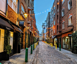 a pretty street at night with lights around shops