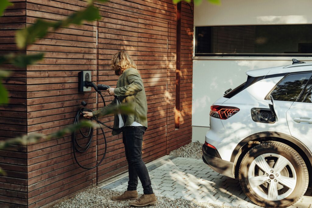 Person charging an electric car at home, highlighting the importance of GAP insurance for electric vehicles.